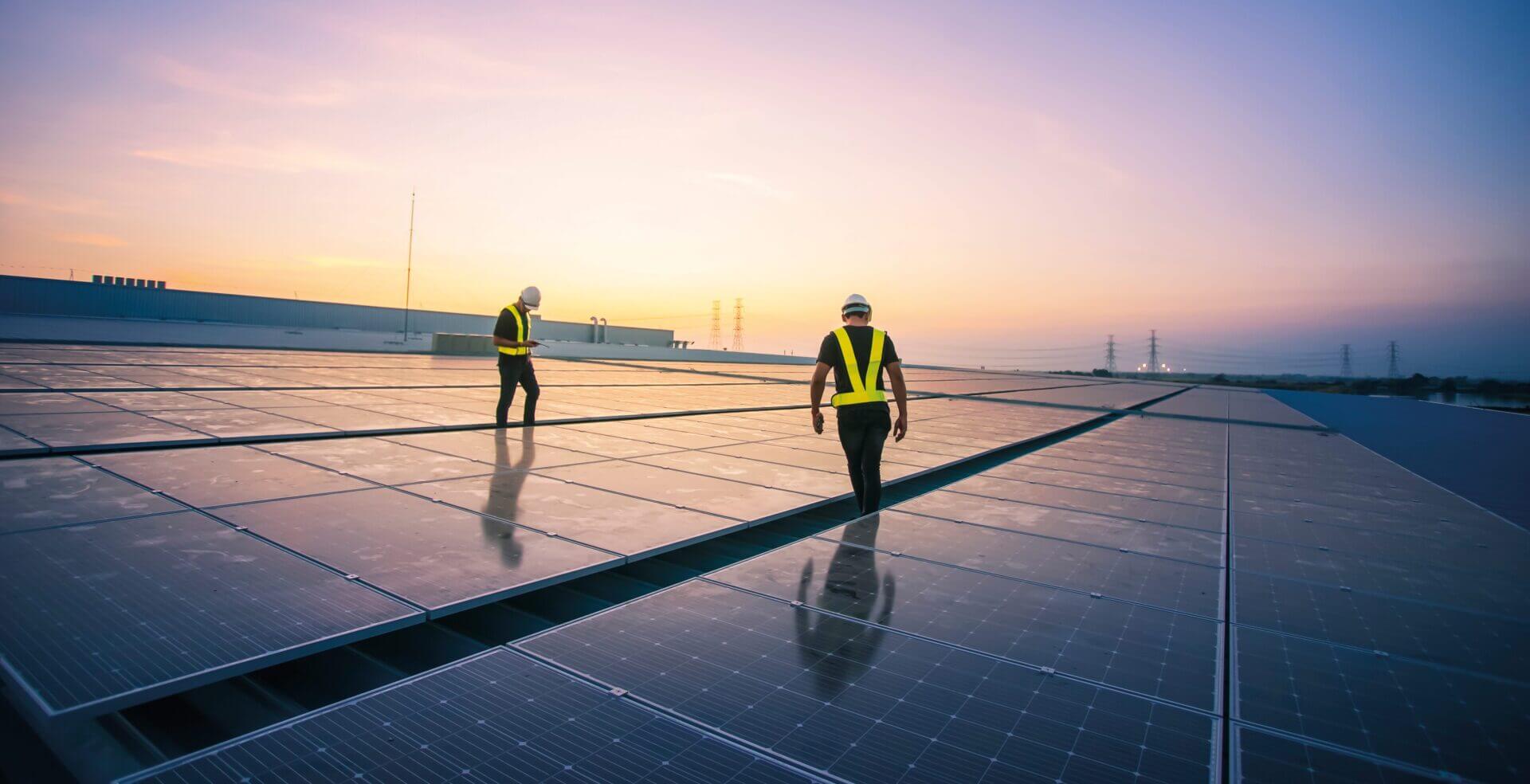 two men on commercial warehouse roof checking solar panels